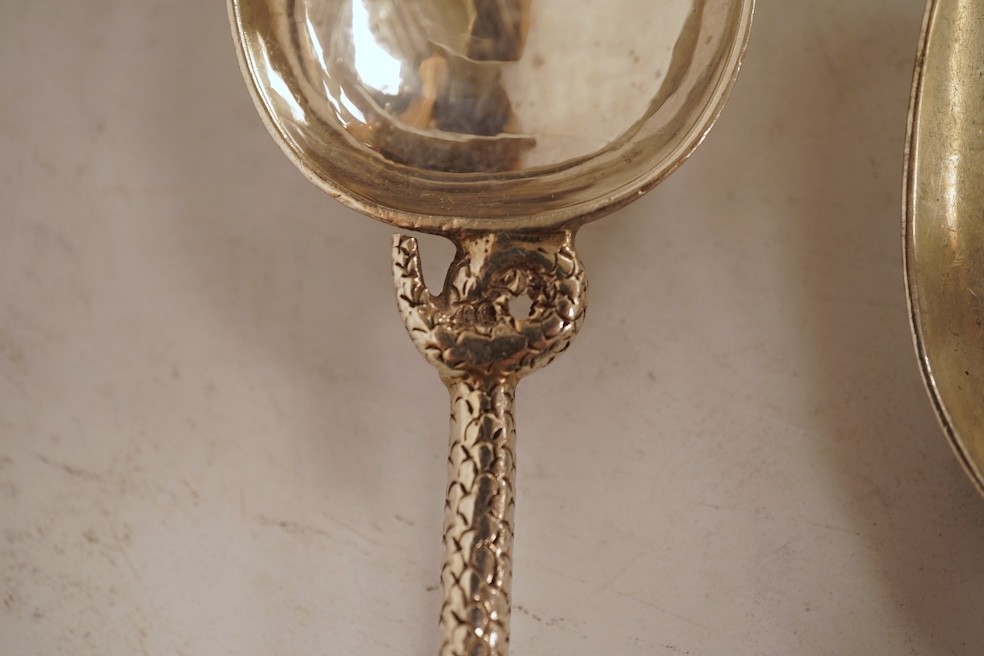 An 18th century silver apostle spoon, indistinct marks, 17cm, a continental white metal spoon with scroll handle and a pair of unmarked white metal spoons with serpent handles.